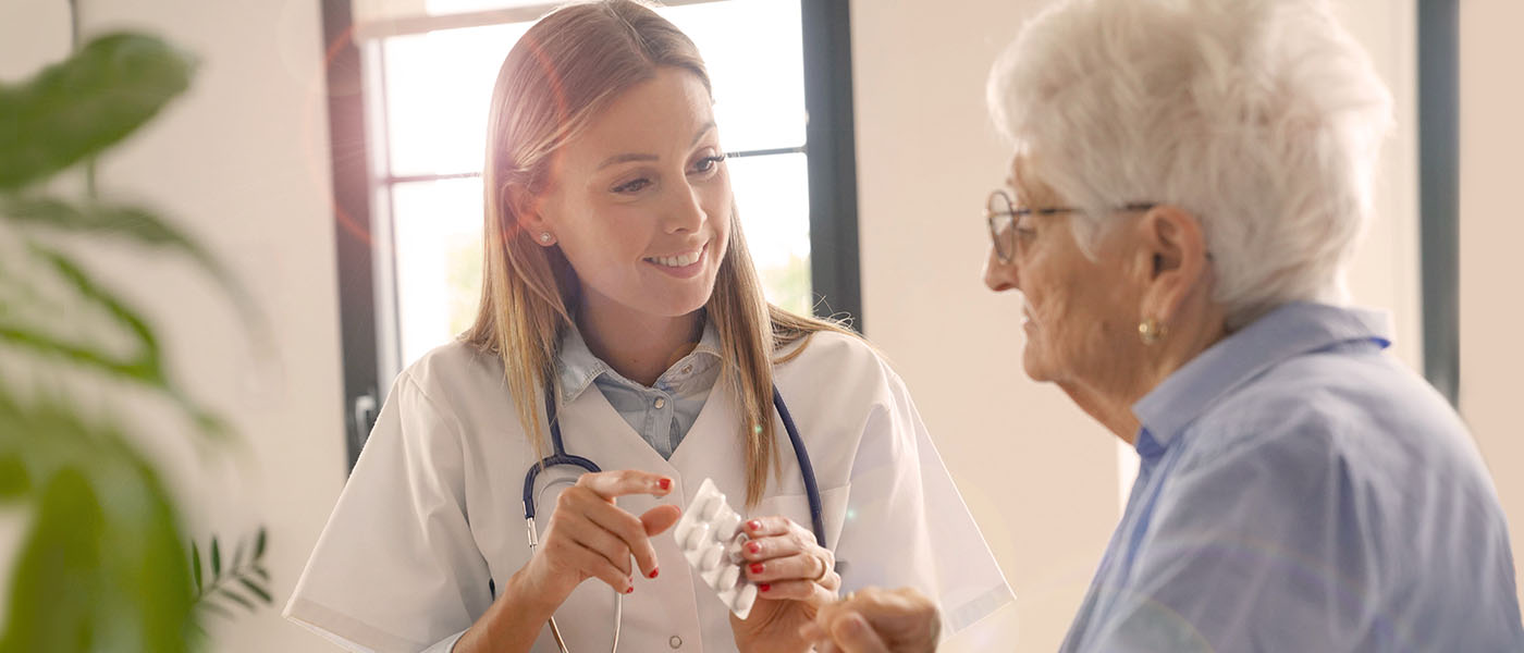 Pflegerin hilft älterer Dame bei der Medikamenteneinnahme